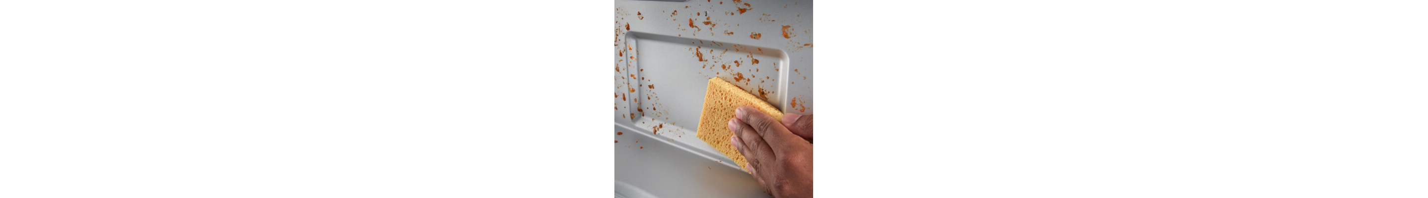 Person wiping down splatters inside the microwave