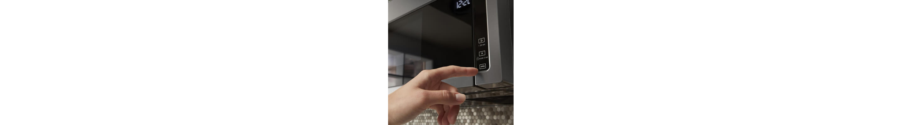 Person pressing touch controls on over-the-range microwave