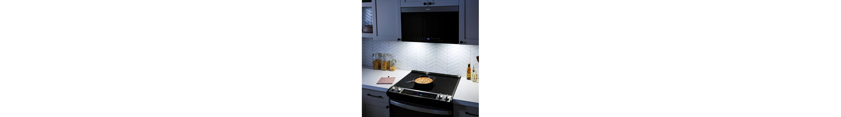 Lighting on over-the-range microwave illuminating a dish cooking on stovetop