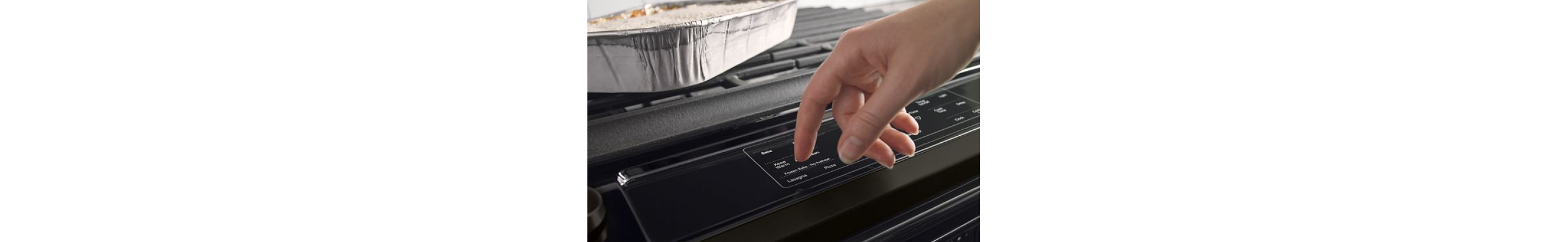A hand pressing the buttons on a stove to preheat the oven