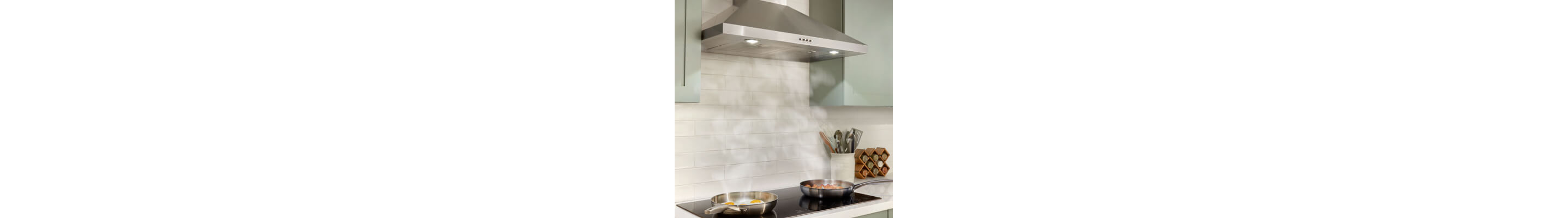 Stainless steel range hood over two pans cooking on a cooktop