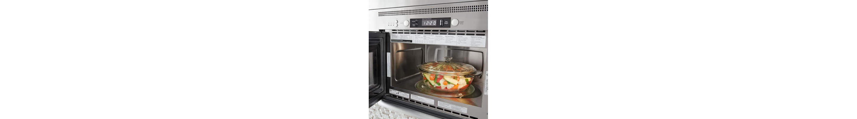 Open over-the-range microwave with a bowl of vegetables inside
