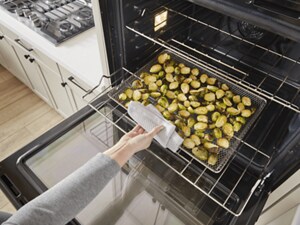 Someone pulling a tray of vegetables out of their oven