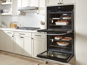 A double wall oven, with both doors open, full of various pans of food