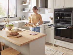 A woman takes a tray of food out of her Whirlpool® Double Wall Oven