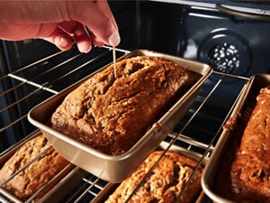 Someone using a toothpick to test the doneness of bread in an oven