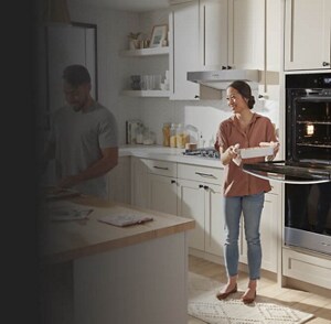 A woman pulling a pan out of her wall oven