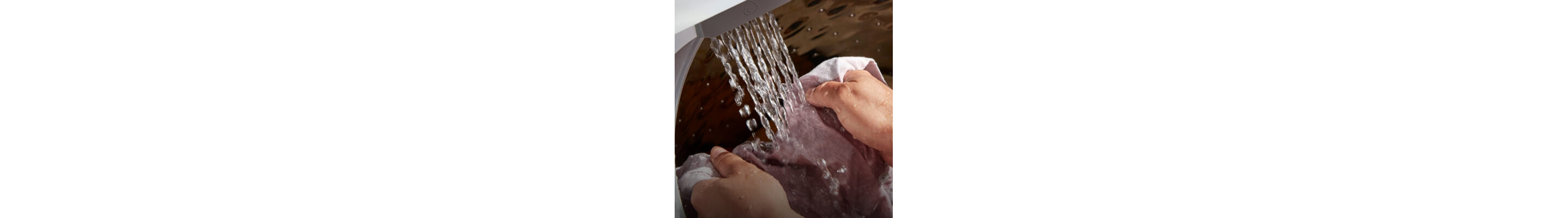 Close up of the interior of a Whirlpool® Washer filling with water as a person pretreats clothing odor