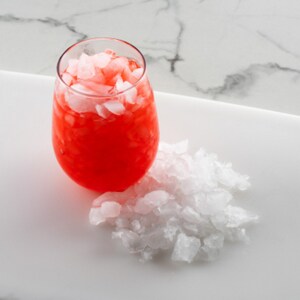 Crushed ice on tray and in a glass with red beverage