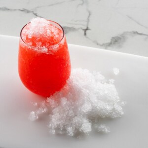 Shaved ice on tray and in a glass with red beverage