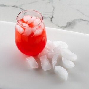 Crescent ice on tray and in a glass with red beverage