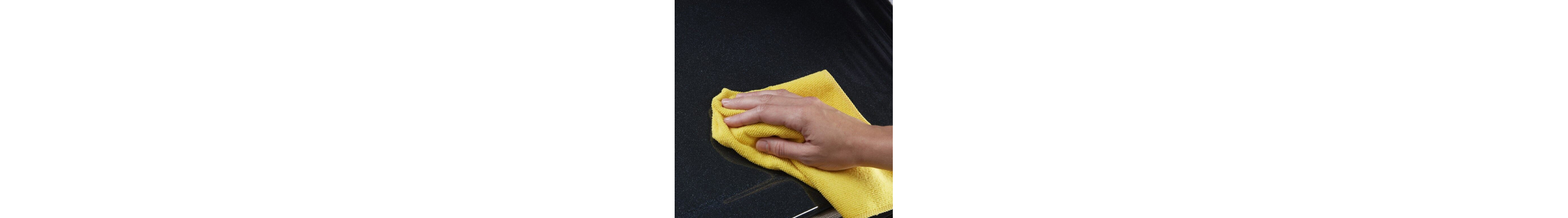 Person cleaning a cooktop with a yellow dish rag