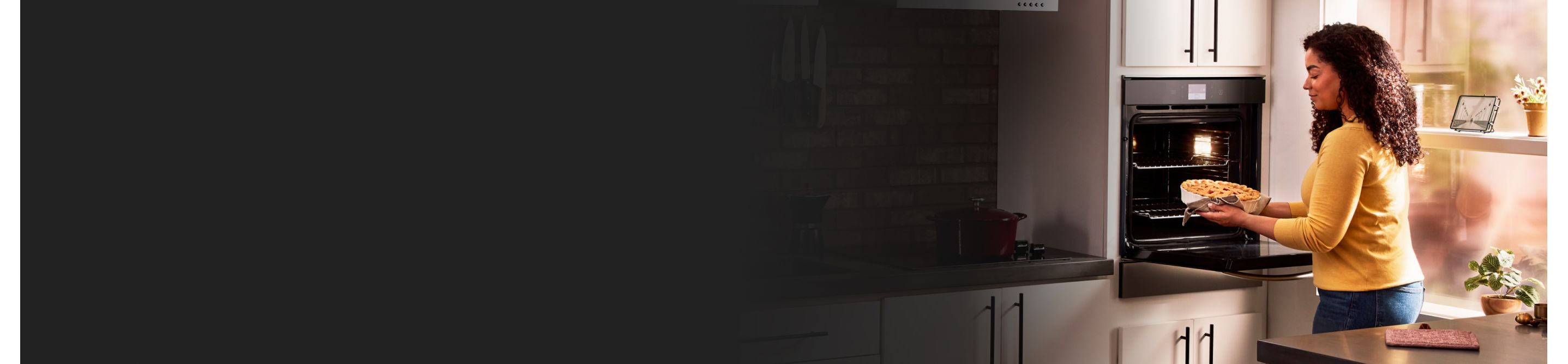 A woman pulling a baked dish out of a single wall oven