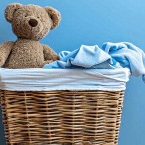 A teddy bear in a basket with a blue blanket