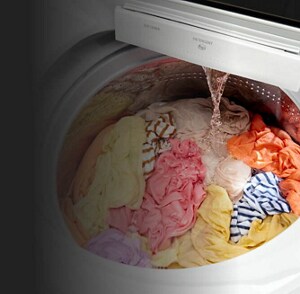 A washer filled with clothing as water pours in