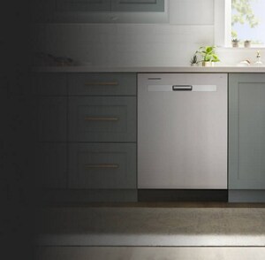A closeup of a stainless steel dishwasher in a kitchen with green cabinetry