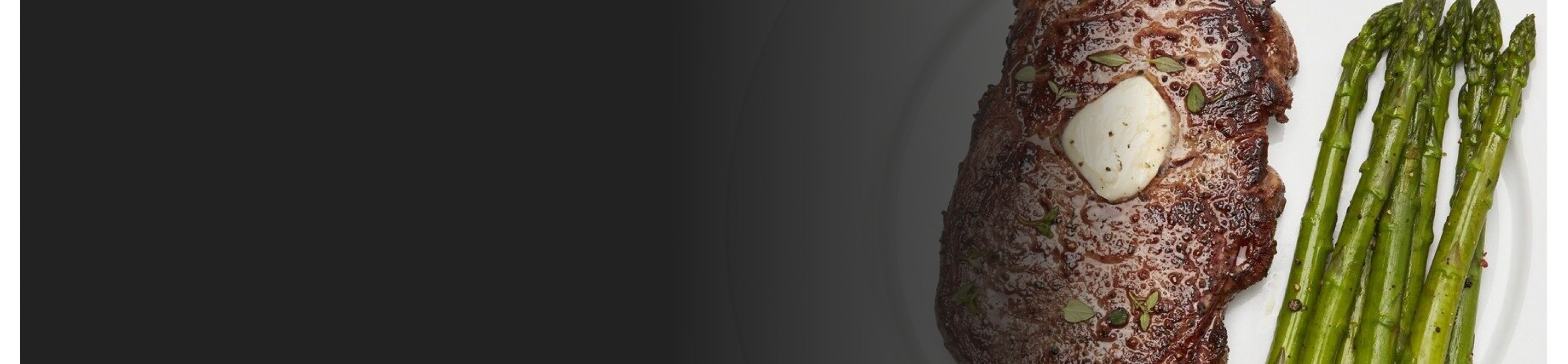 A butter garnished steak dish with asparagus on the side