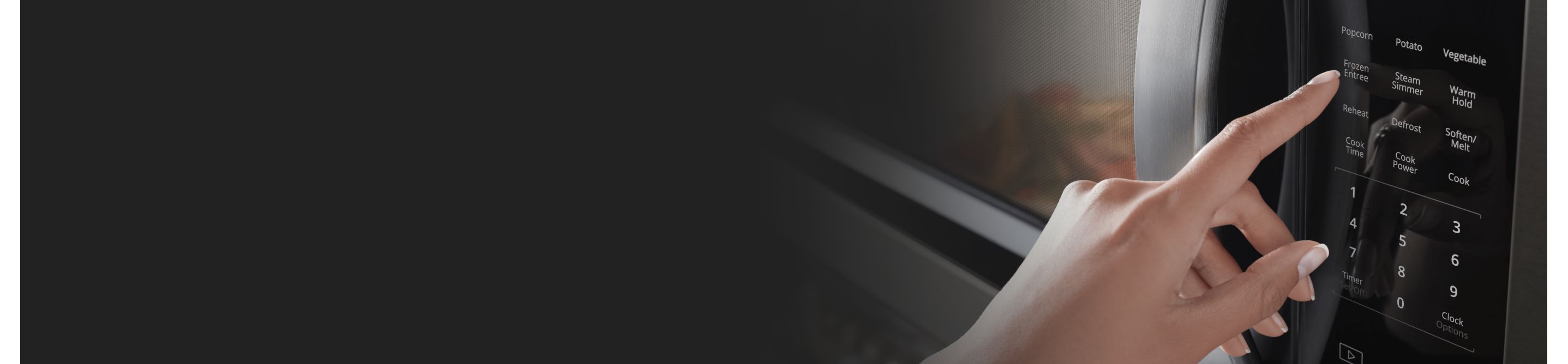 A closeup of a person’s hand programming a setting on a Whirlpool® microwave.