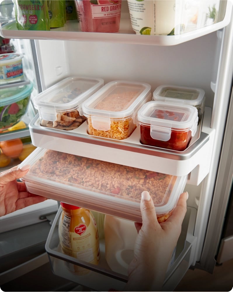 A hand removing a leftovers inside of a built-in storage container from the refrigerators