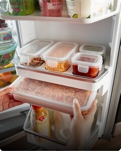 A hand removing a leftovers inside of a built-in storage container from the refrigerators