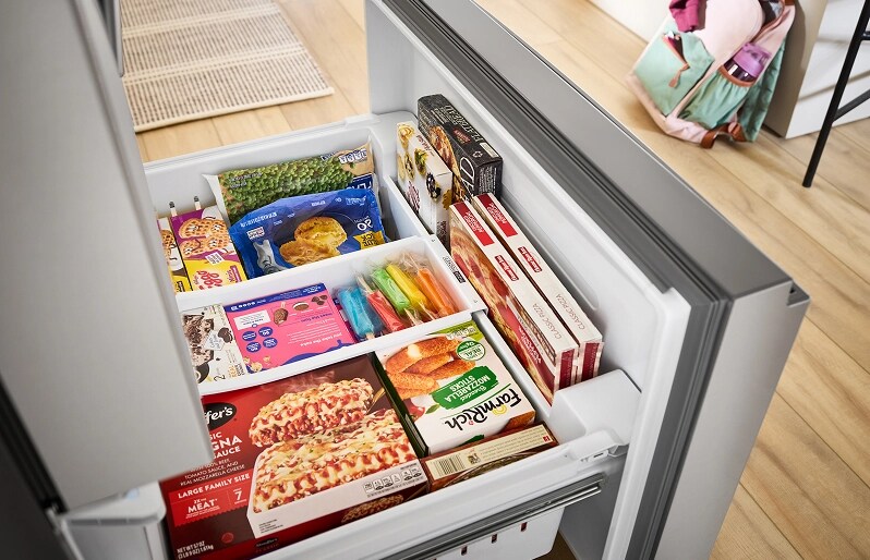 The bottom drawer of a French door refrigerator opened to reveal neatly organized frozen foods
