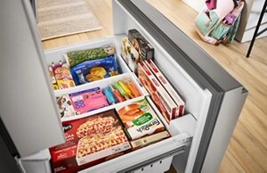 The bottom drawer of a French door refrigerator opened to reveal neatly organized frozen foods