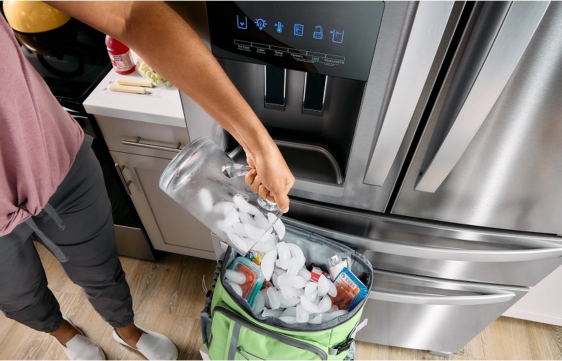 A person filling a cooler with ice cubes from their Whirlpool® Refrigerator's ice dispenser