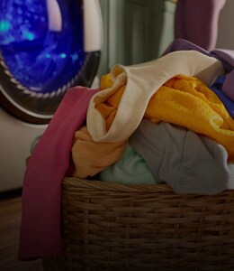 A basket filled with laundry in front of a washing machine