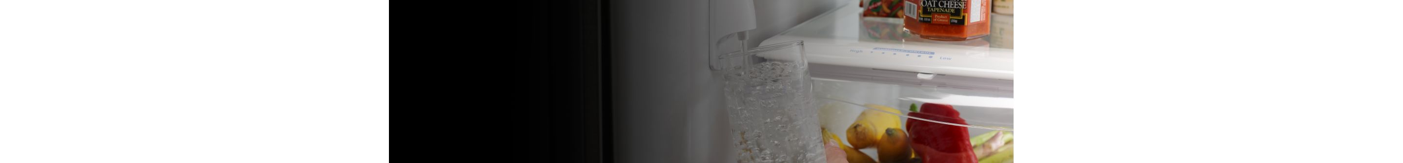 A woman fills up a water bottle from a refrigerator water dispenser.