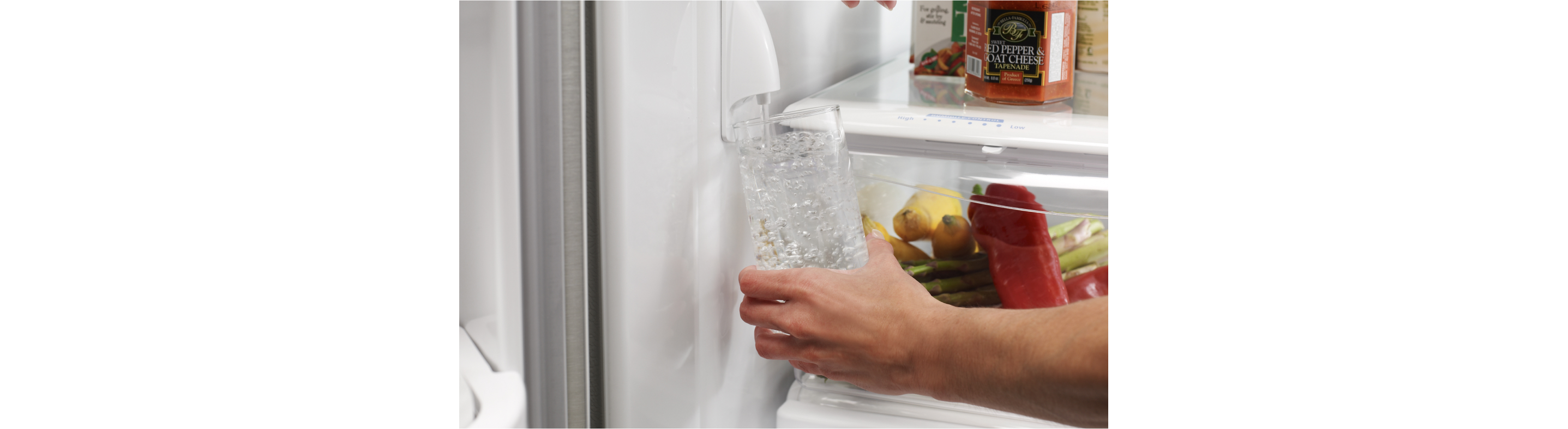 Filling a water glass from a refrigerator water dispenser.